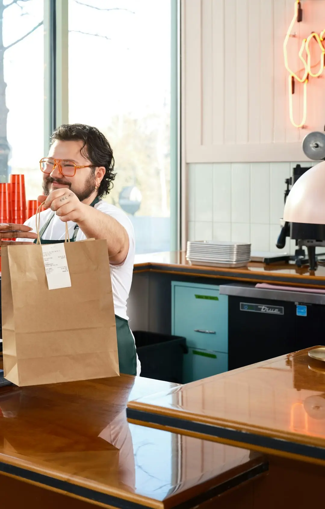 A takeaway bag handed to a customer at a counter